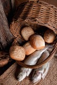 Religious still life of loaves of bread, fishing net, basket and two fresh fish